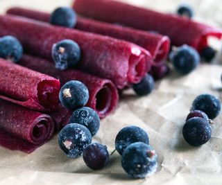 Blueberry fruit leather rolls with fresh blueberries around them