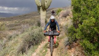 Sarah Sturm descends a dirt road past giant cacti
