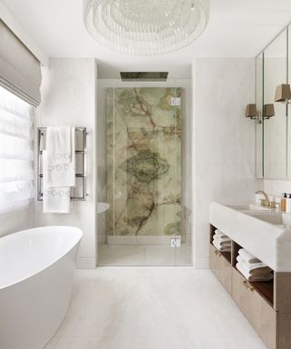 An example of bathroom layout ideas showing a cream bathroom with a white bath and a marble walk-in shower
