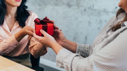 a female office worker giving her coworker a gift