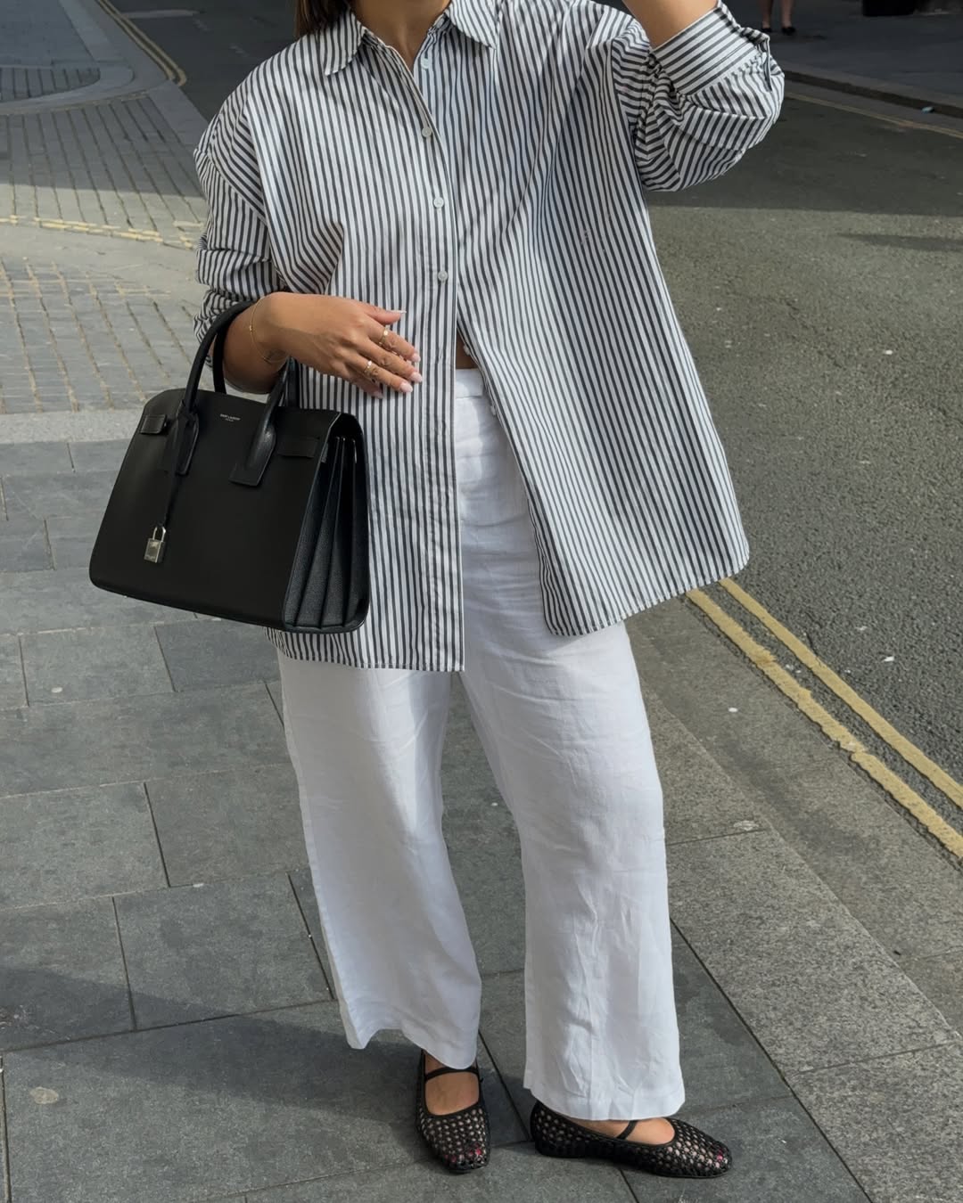 Influencer Tegan Frances wearing a striped shirt, linen trousers and mesh ballet flats.