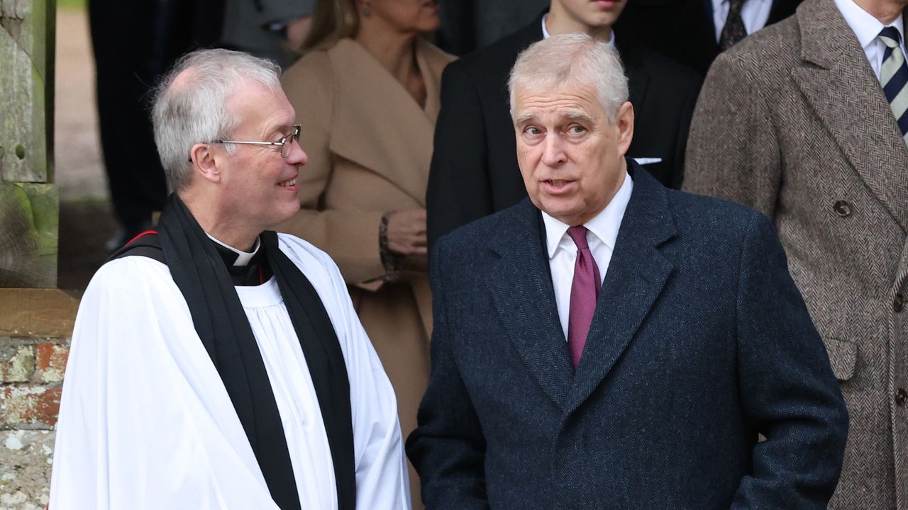 Prince Andrew wearing a coat and tie talking to a minister outside