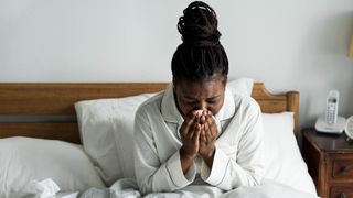 A woman sneezing in bed with allergies