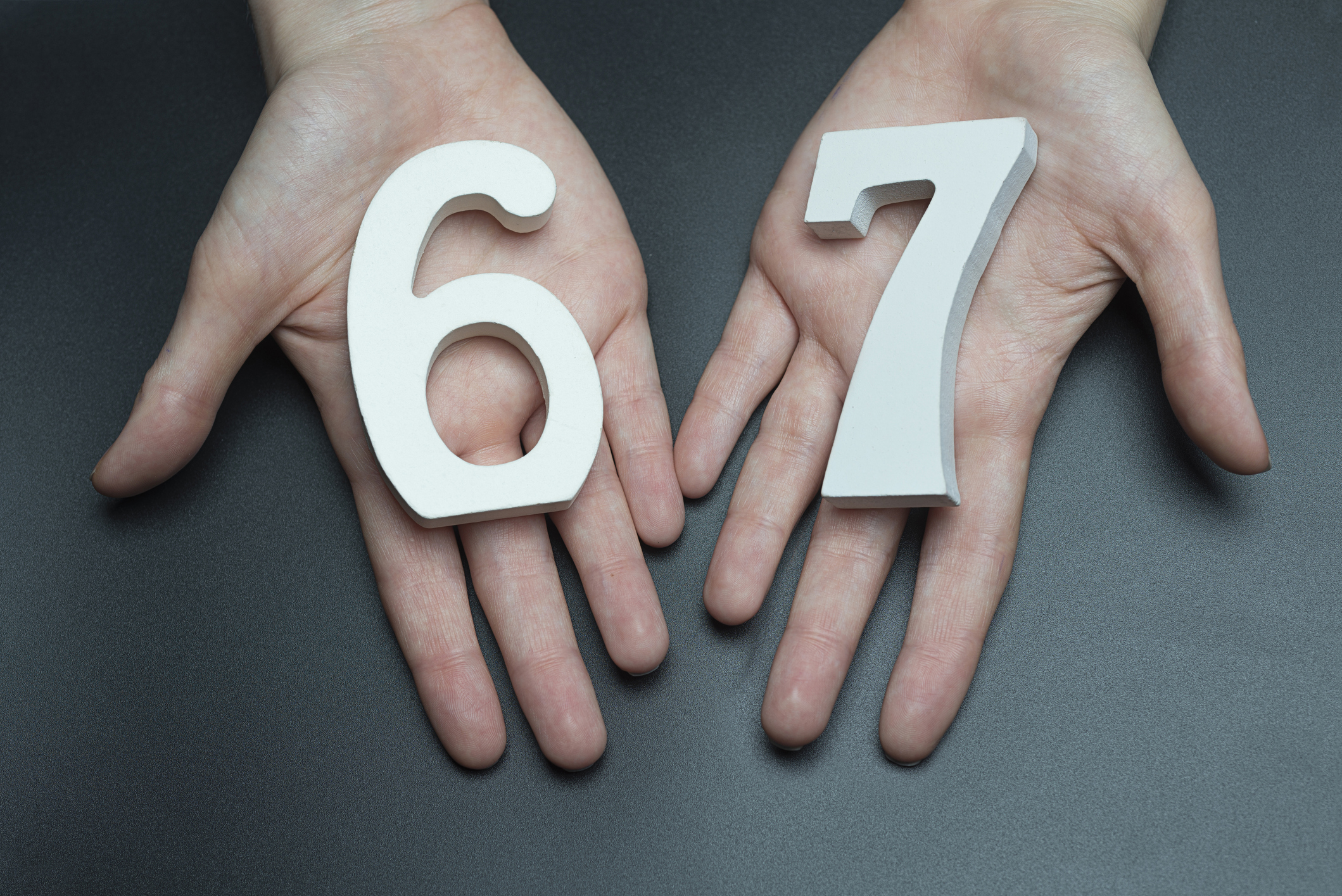 On a black background, female hand with number sixty-seven.