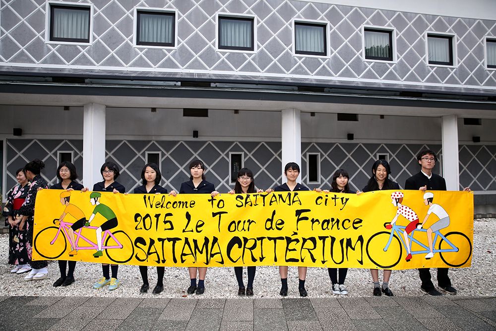 Local students hold up a Saitama Criterium banner
