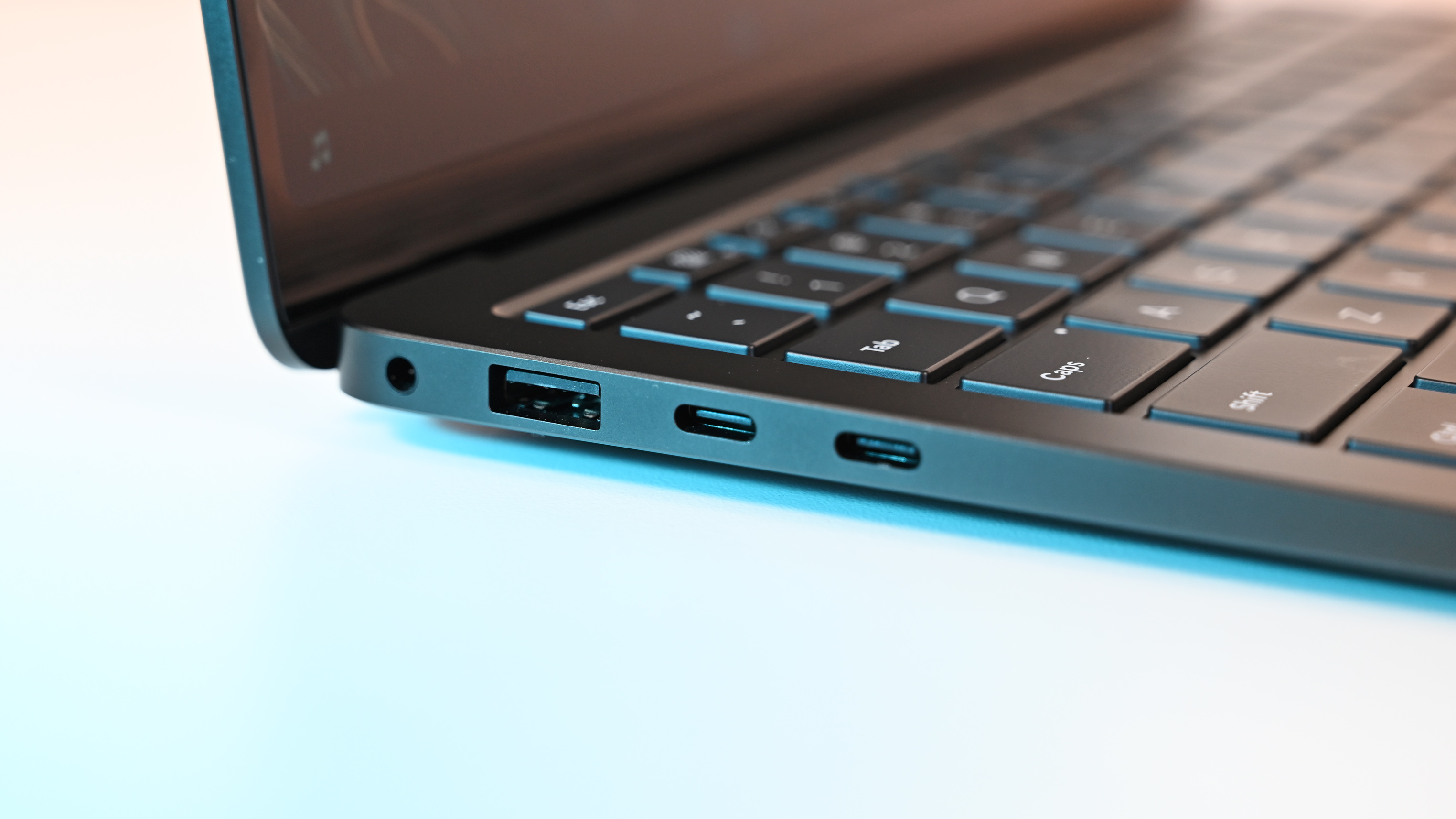 Close-up of Surface Laptop for Business 8th Edition side, showing a USB port, two USB-C ports, and part of the keyboard. The sleek design suggests a modern aesthetic.