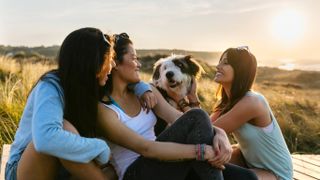 Three women and dog outside at sunset