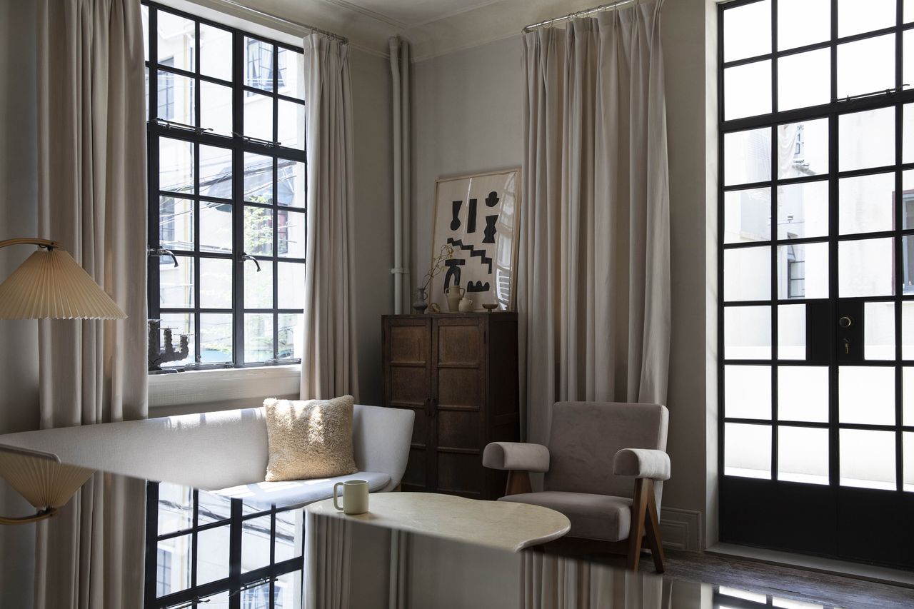 A neutral colored room with curtain rails supporting pale pink fabric