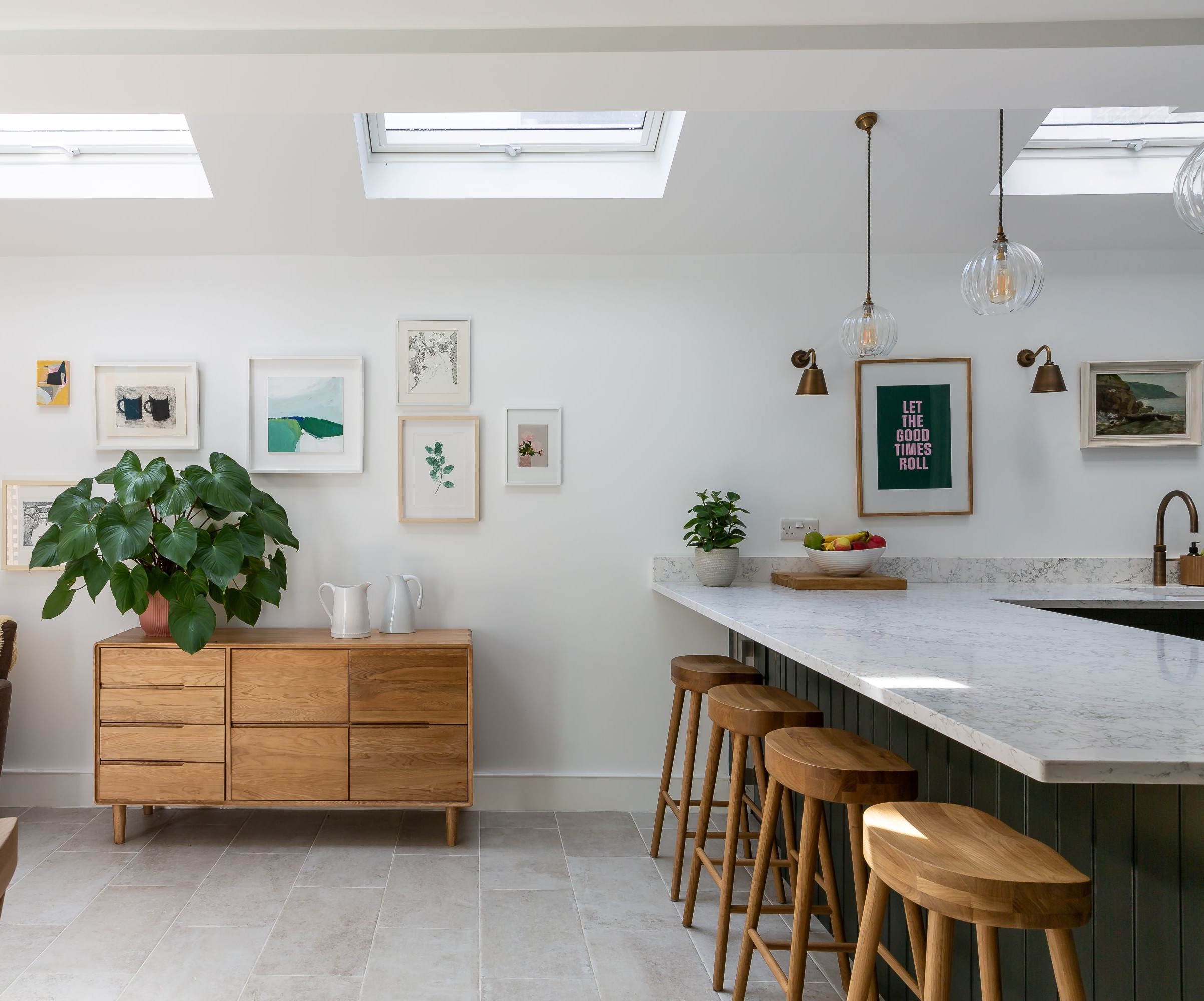 A kitchen with a marble worktop and oak stools and roof lights overhead