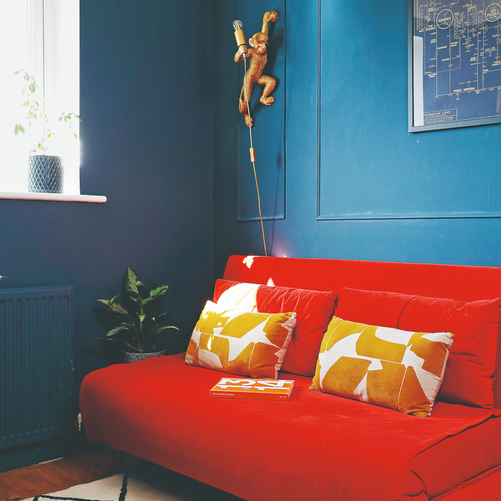 A blue living room with a bright red sofa bed