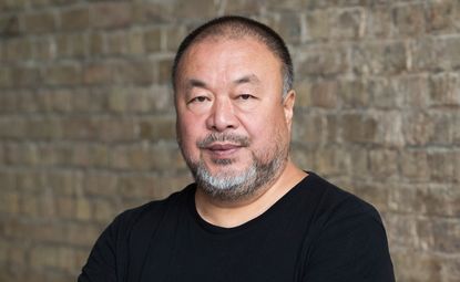 Portrait of Chinese artist Ai Weiwei in his studio with brick background 