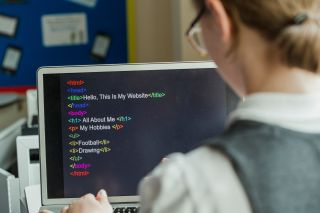 Female student creates HTML code on laptop computer