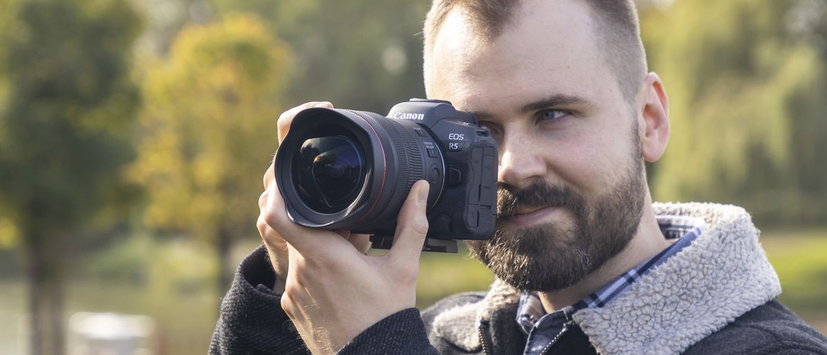 Photographer holding the Canon RF 10-20mm f/4L IS STM mounted to a Canon EOS R5