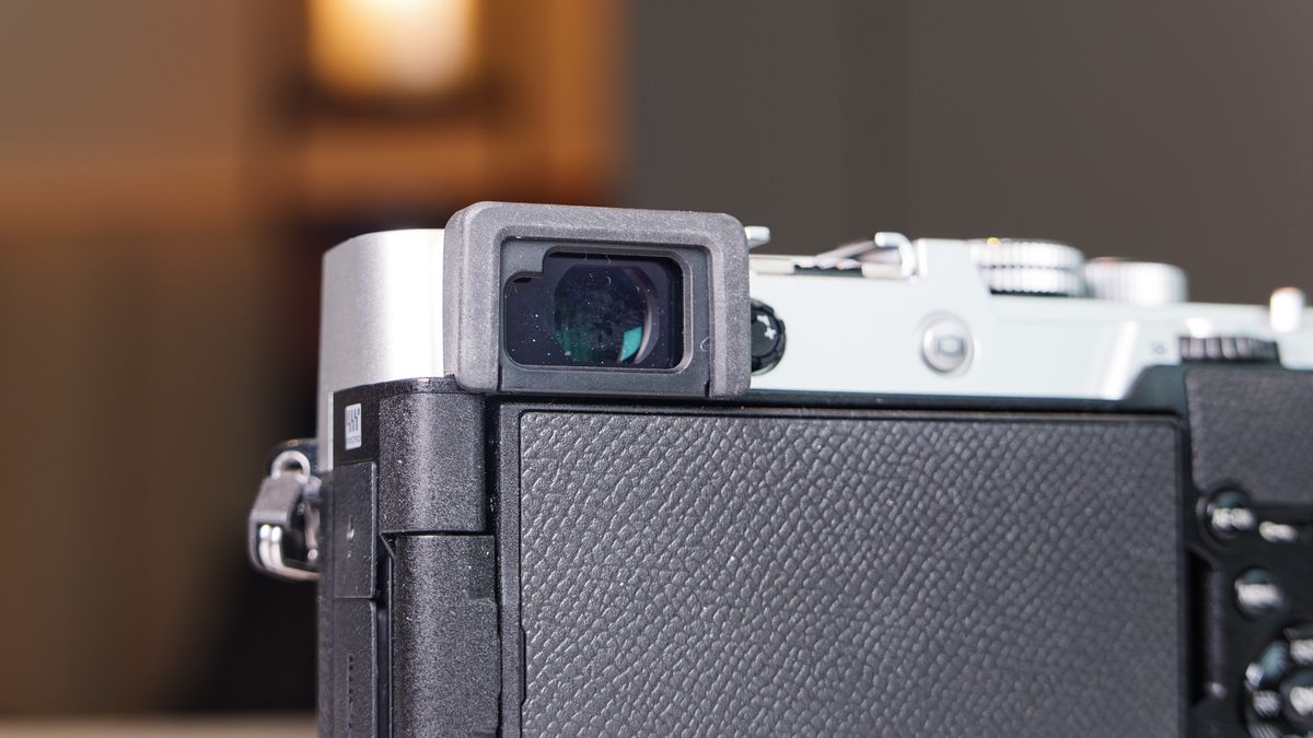 Close up of the OM System PEN mirrorless camera's viewfinder, in a modern room with lantern in the background