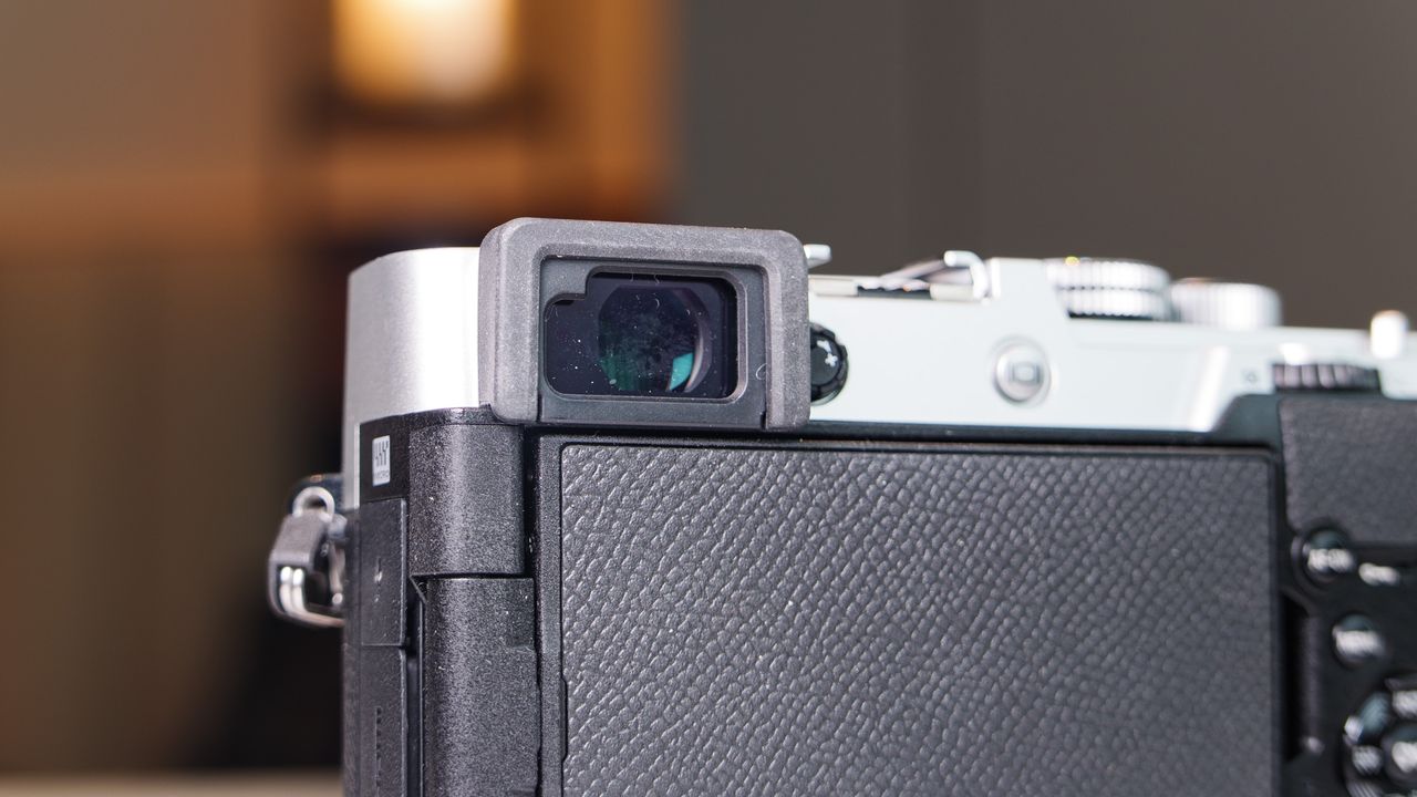 Close up of the OM System PEN mirrorless camera's viewfinder, in a modern room with lantern in the background