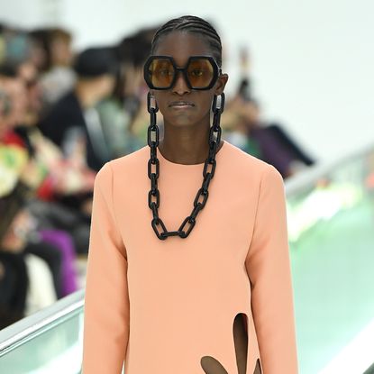 A beautiful model walks the runway for Gucci with her hair set in neat cornrows