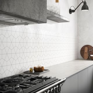 Grey slab kitchen with white worktops and white geometric tiled splashback