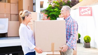 Mature couple unloading box from moving van