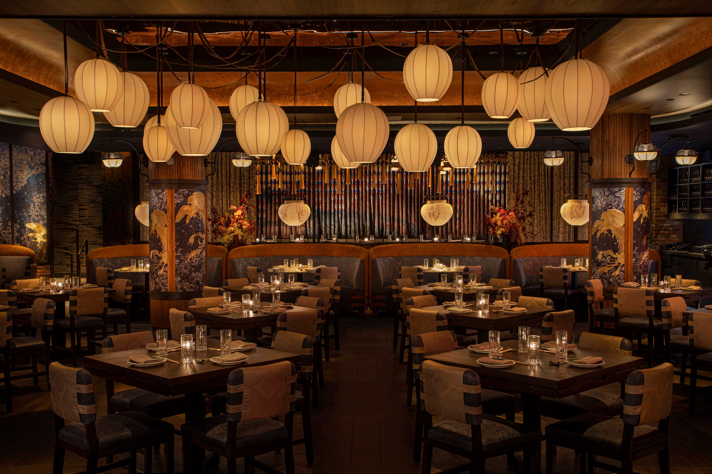 A layeredly decorated hotel features extravagant decor in its communal areas, including sumptuous chandelier, paper lanterns, lush plants, and patterned upholstery, with quirky, contemporary rooms characterized by color-block interiors and textural surfaces.