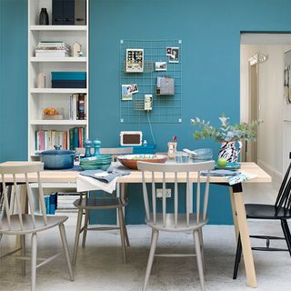 A dining room with teal walls and a wooden dining table