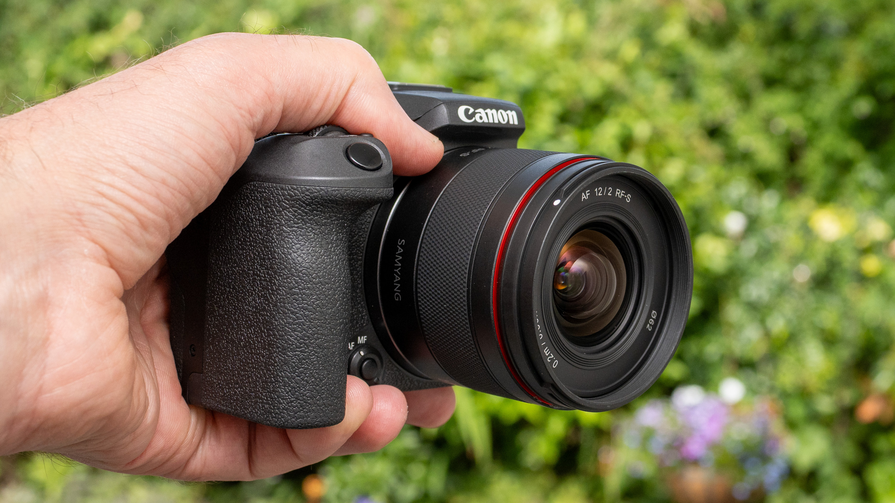 LK Samyang AF 12mm f/2 RF-S product shot lens held in hand