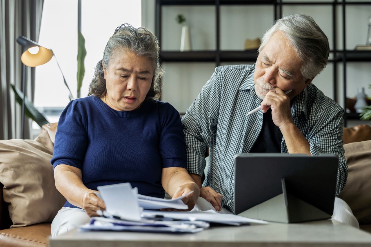 Older woman and man looking at paperwork and laptop