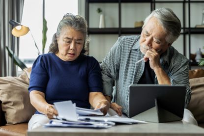 Older woman and man looking at paperwork and laptop