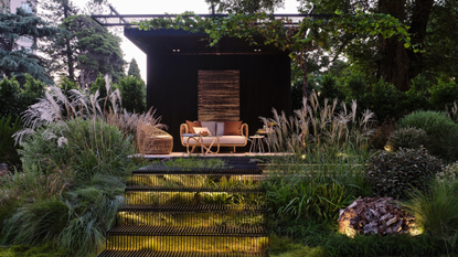 raised garden seating area with backlit stairs and beautiful tall foliage all around 