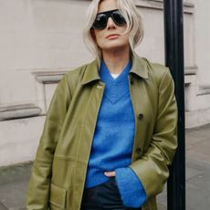 Woman in a blue sweater, green jacket, and jeans
