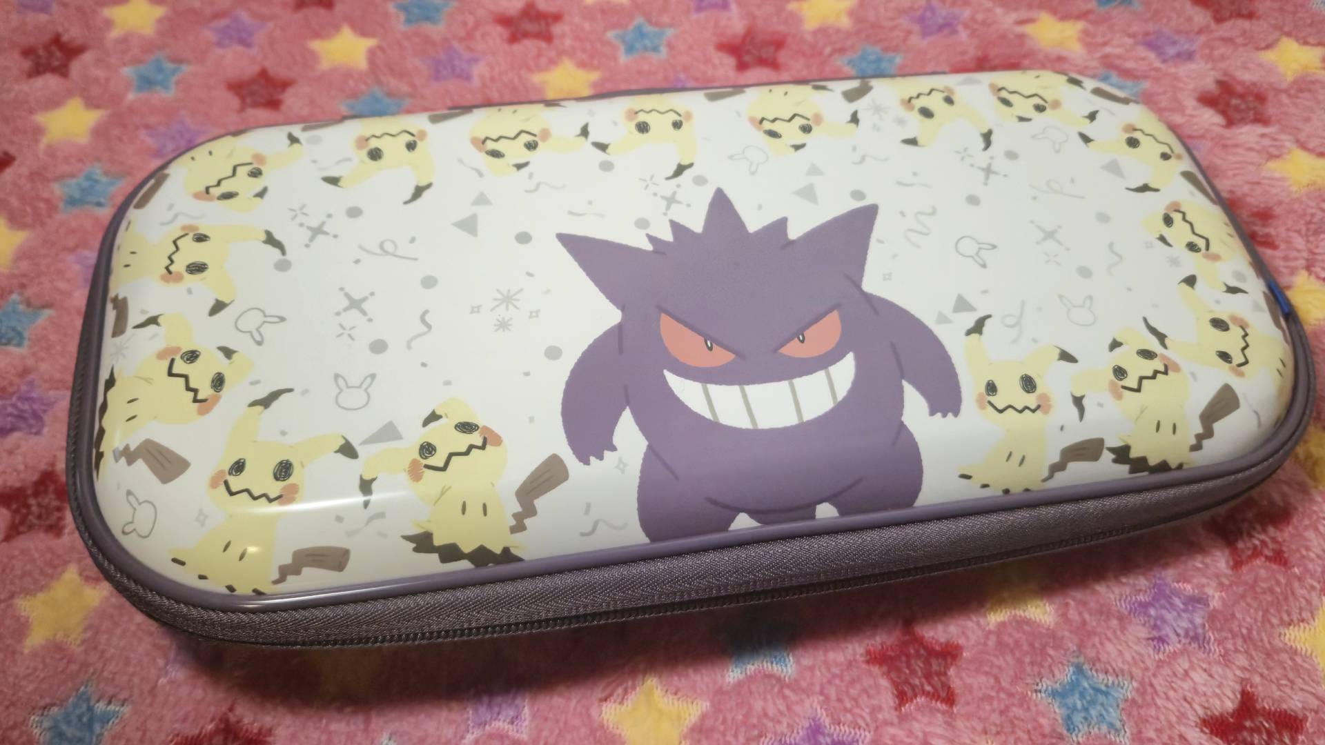 Image of the Hori Gengar and Mimikyu Vault Case sitting on a pink star patterned blanket.