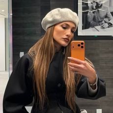 J.lo wears a gray beret and a black top.
