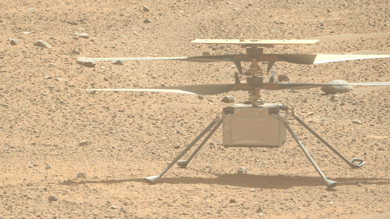 a small helicopter sits on dusty reddish-orange dirt