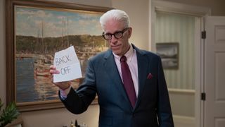 Charles holds up a note saying 'Back off' in A Man on the Inside.