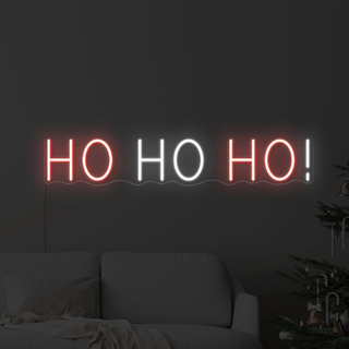 A neon sign in a dark living room with festive text reading 'Ho ho ho'