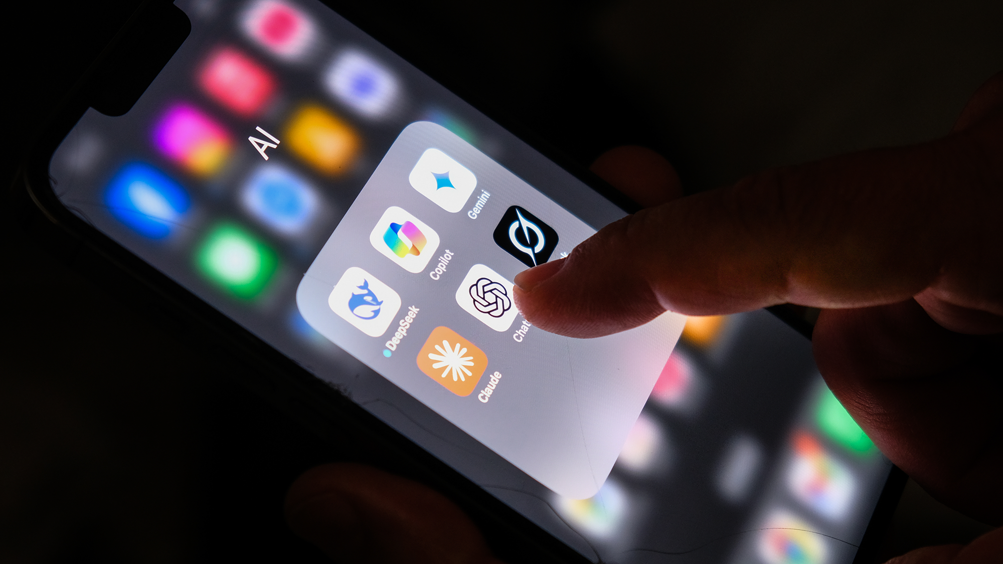 A close up of a hand touching a series of apps on a smartphone, with the thumb hovering over the ChatGPT logo