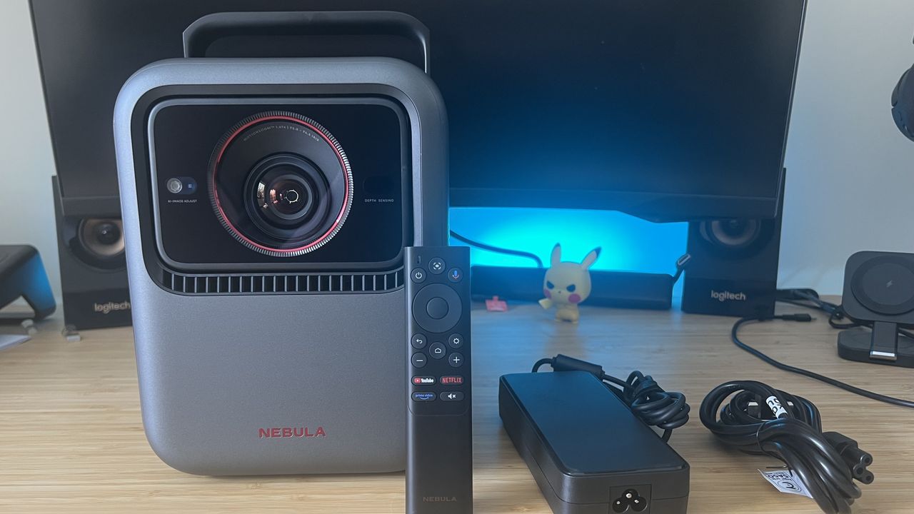 Anker Nebula X1 projector with remote control and power cables on a wooden desk