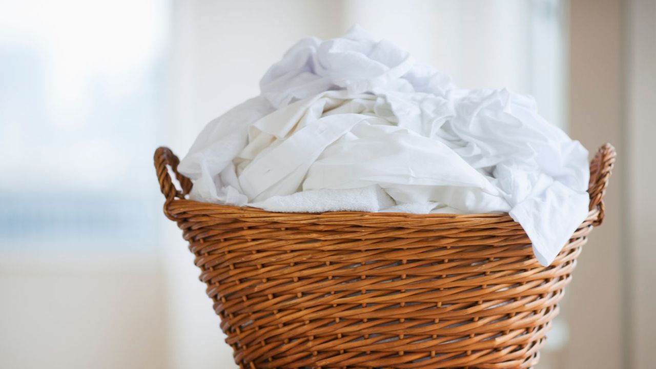 A wicker landry basket with white washing piled up inside