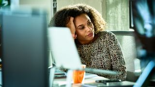 Woman at desk worried, head in hand pondering on stress vs anxiety