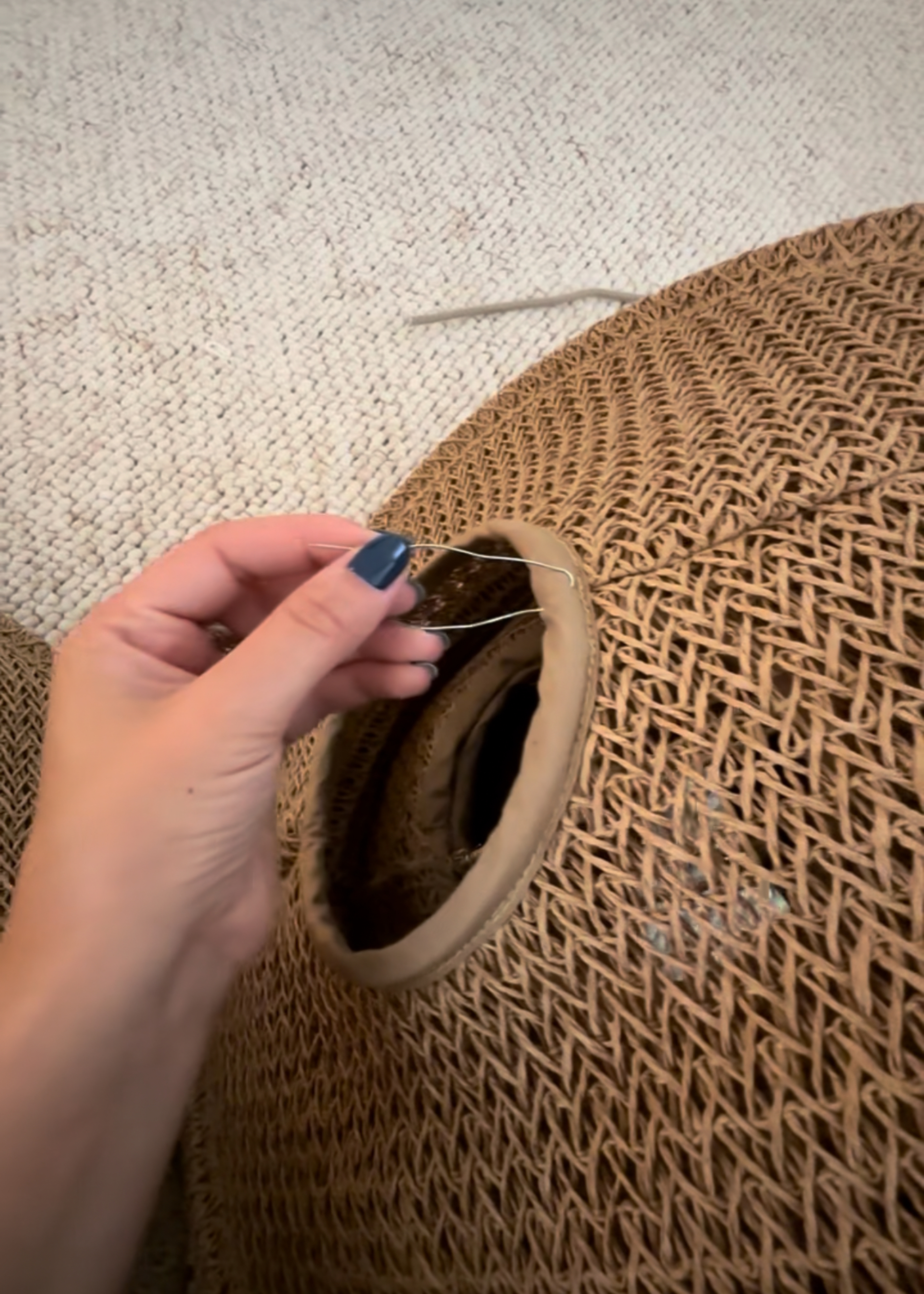 A close up of a woven lampshade being threaded with wire