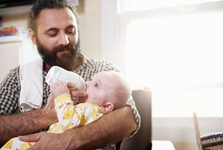 A man bottle feeding a baby