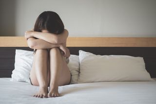 Vaginal dryness treatment: Depressed woman sitting on bed