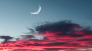 New Moon July 2022: Fluffy pink, purple and grey clouds with Crescent Moon during sunset. Cumulus Congestus Clouds - stock photo