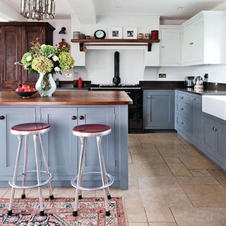 kitchen with white wall grey cabinets wooden counter and round stool