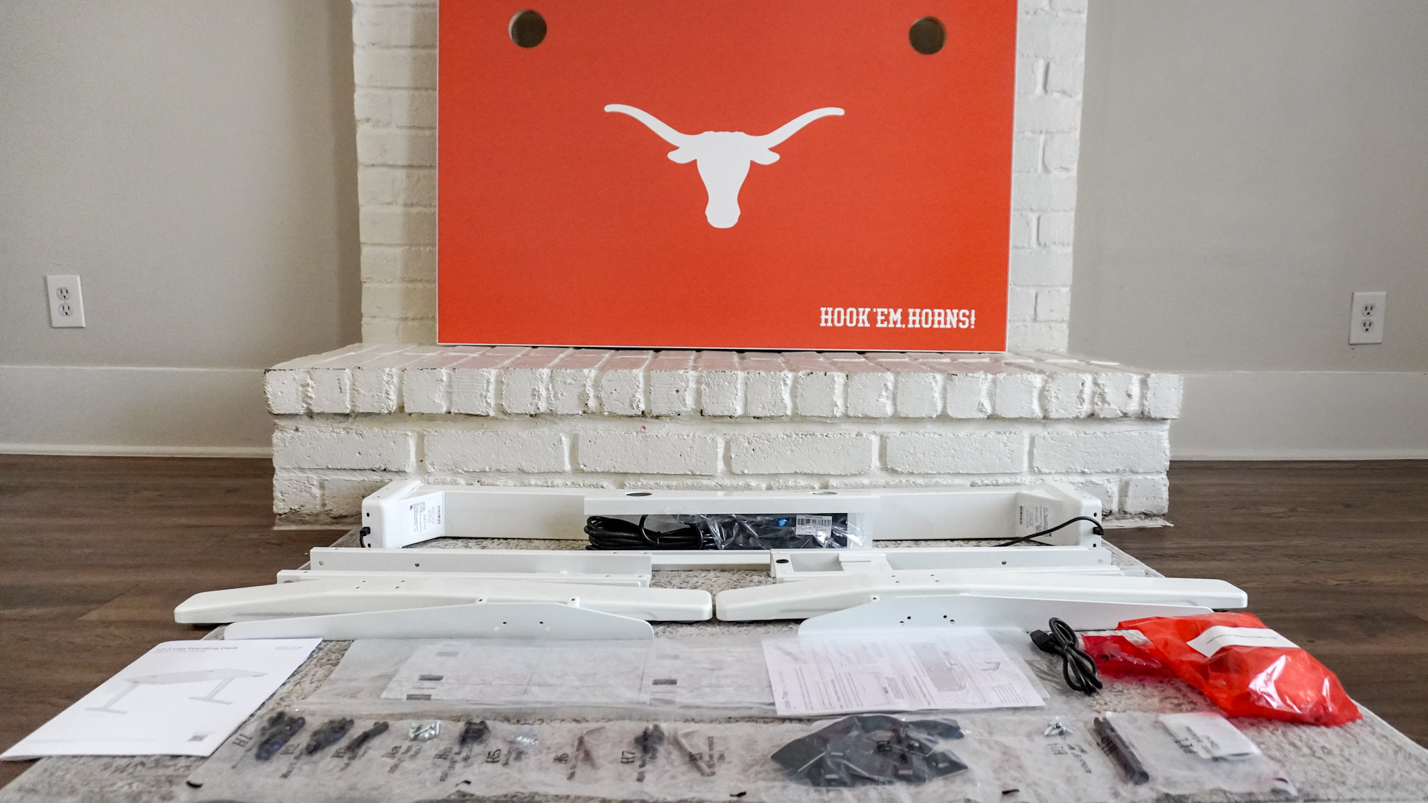 All the parts of the University of Texas desk from the Uplift Desk Collegiate Collection laid out on a carpet in front of a fireplace