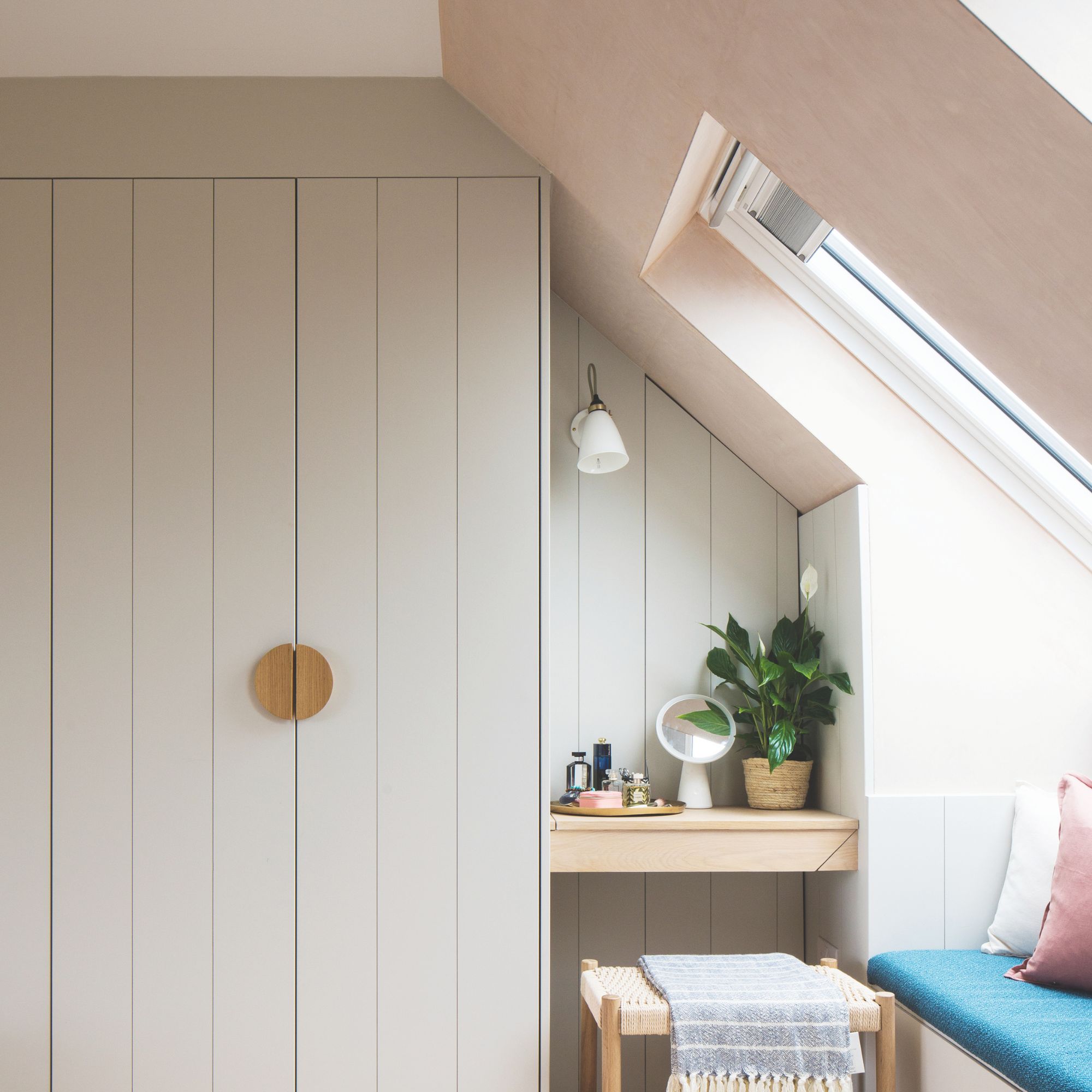 Built-in dressing area with built-in wardrobe space under Velux window with seating