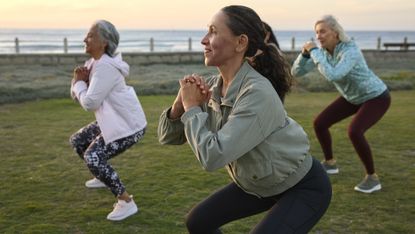 Group of women in activewear outside performing the squat movement