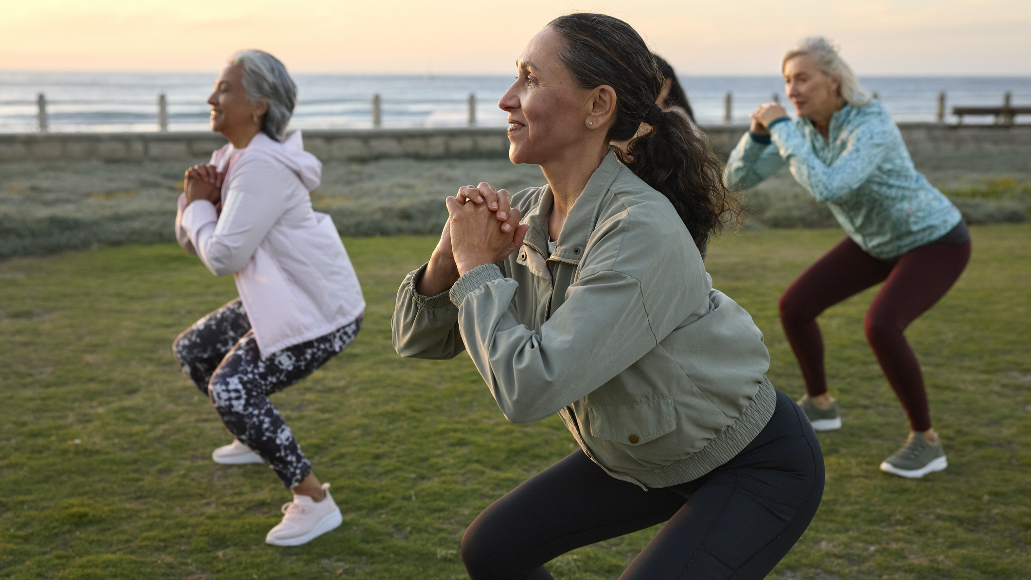 Group of women in activewear outside performing the squat movement