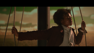 Close-up video still of a young black female against the night sky, holding on to the ropes of a ship's mast whilst closing her eyes.