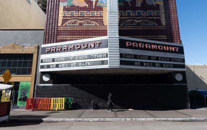 A person walks under a marquis for a closed down Paramount theater