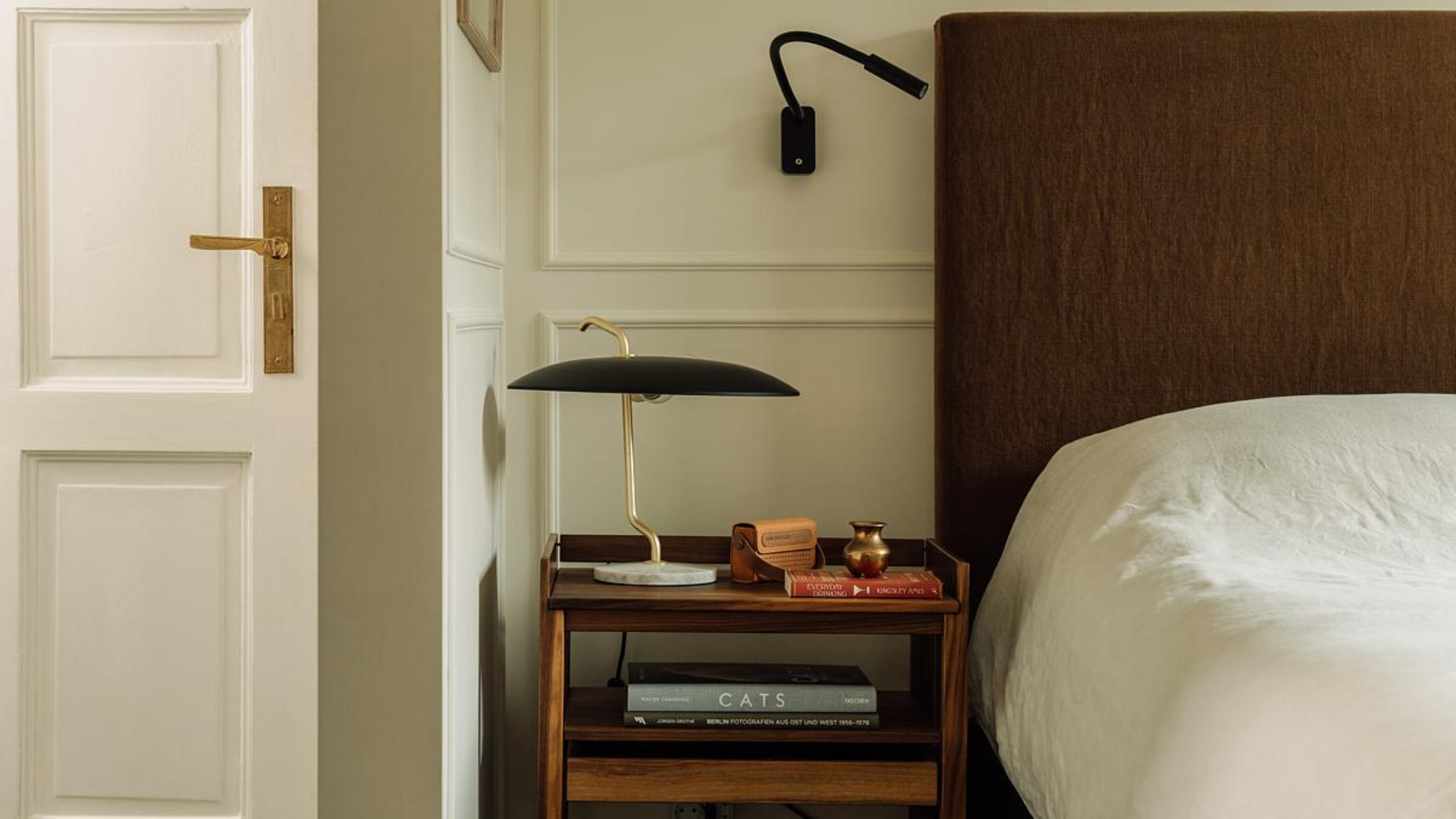 A bedside table with lamp and wall light